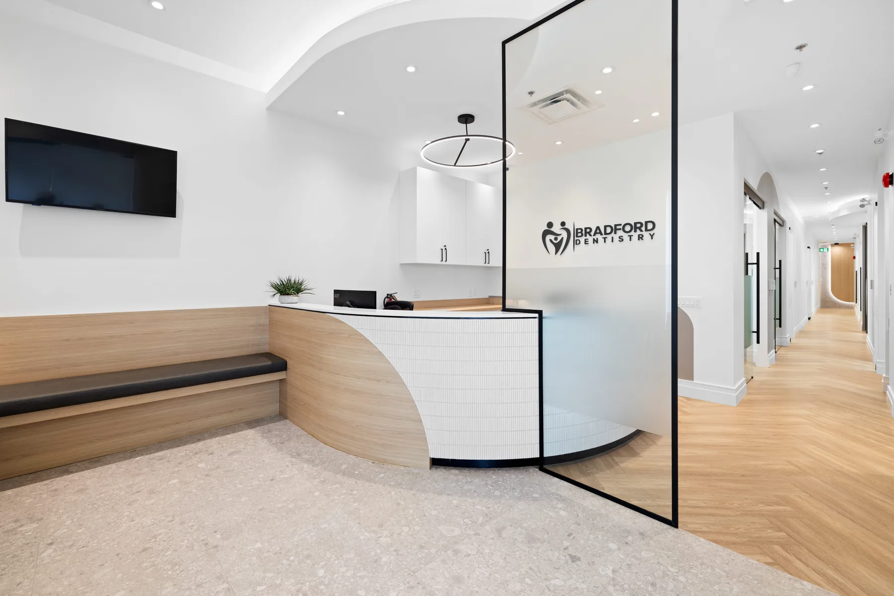 Bright curved reception desk and waiting area at Bradford Dentistry